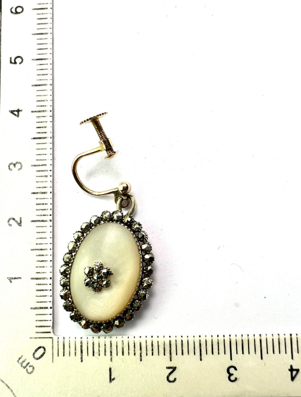 A pair of oval Georgian drop earrings featuring mother of pearl cabochons framed by faceted marcasite stones with a central marcasite floral cluster. View VII
