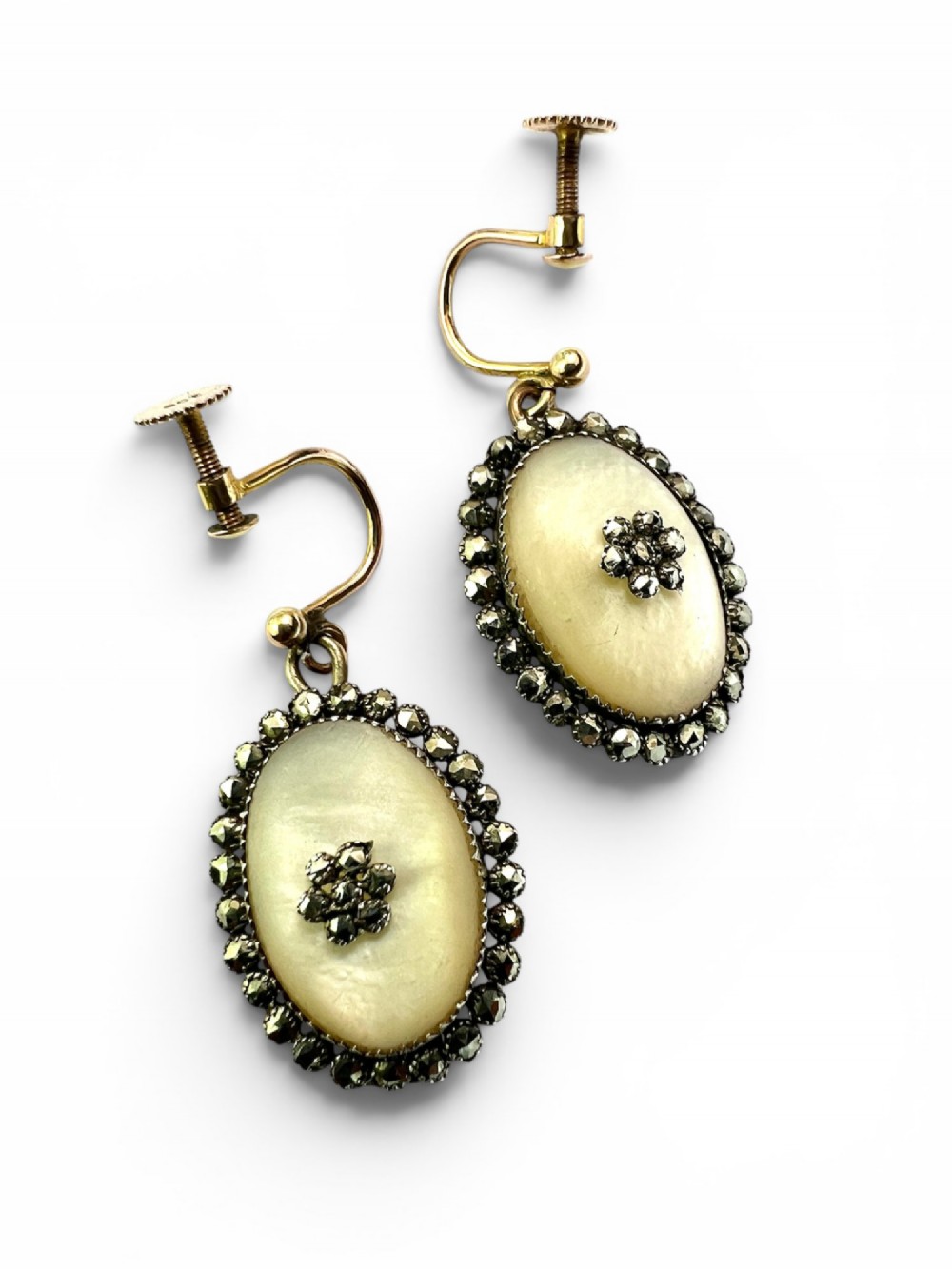 A pair of oval Georgian drop earrings featuring mother of pearl cabochons framed by faceted marcasite stones with a central marcasite floral cluster. View VIII