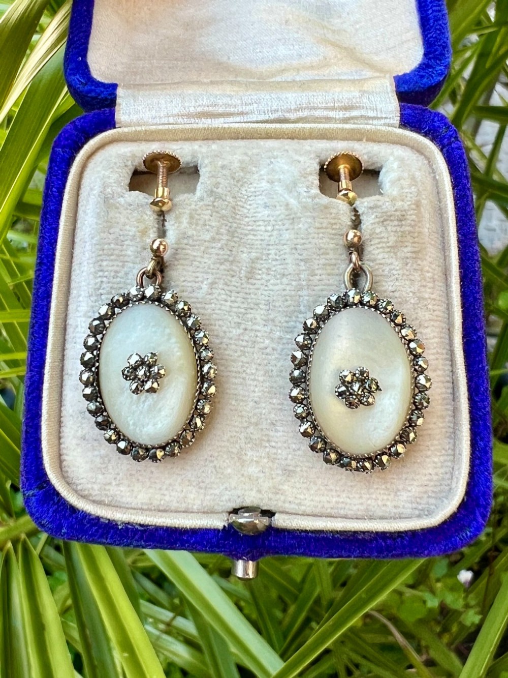 A pair of oval Georgian drop earrings featuring mother of pearl cabochons framed by faceted marcasite stones with a central marcasite floral cluster. View IX