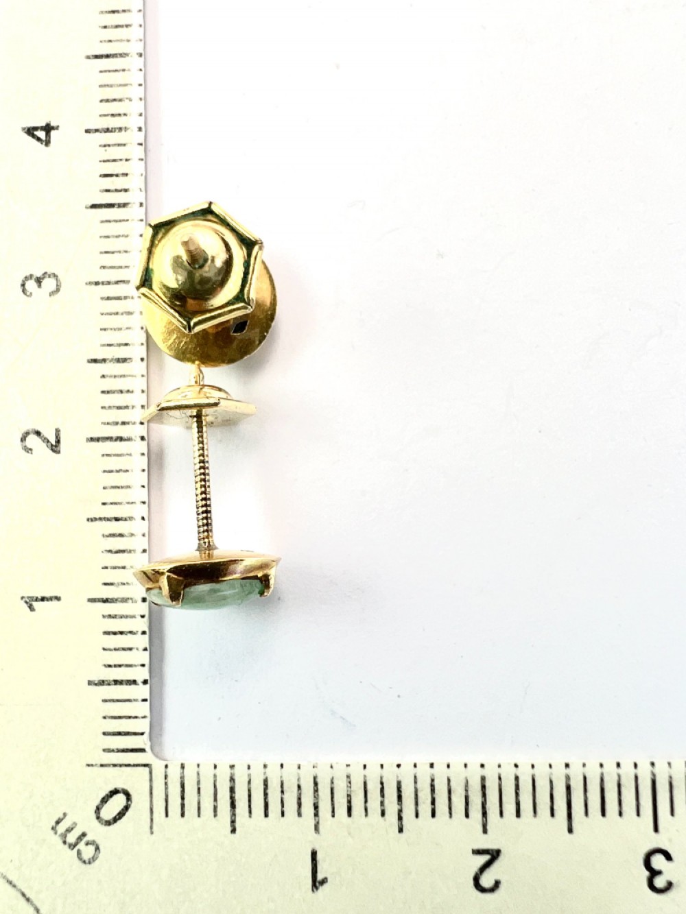 A pair of circular pale green jadeite cabochon stud earrings held in yellow gold claw settings. View III