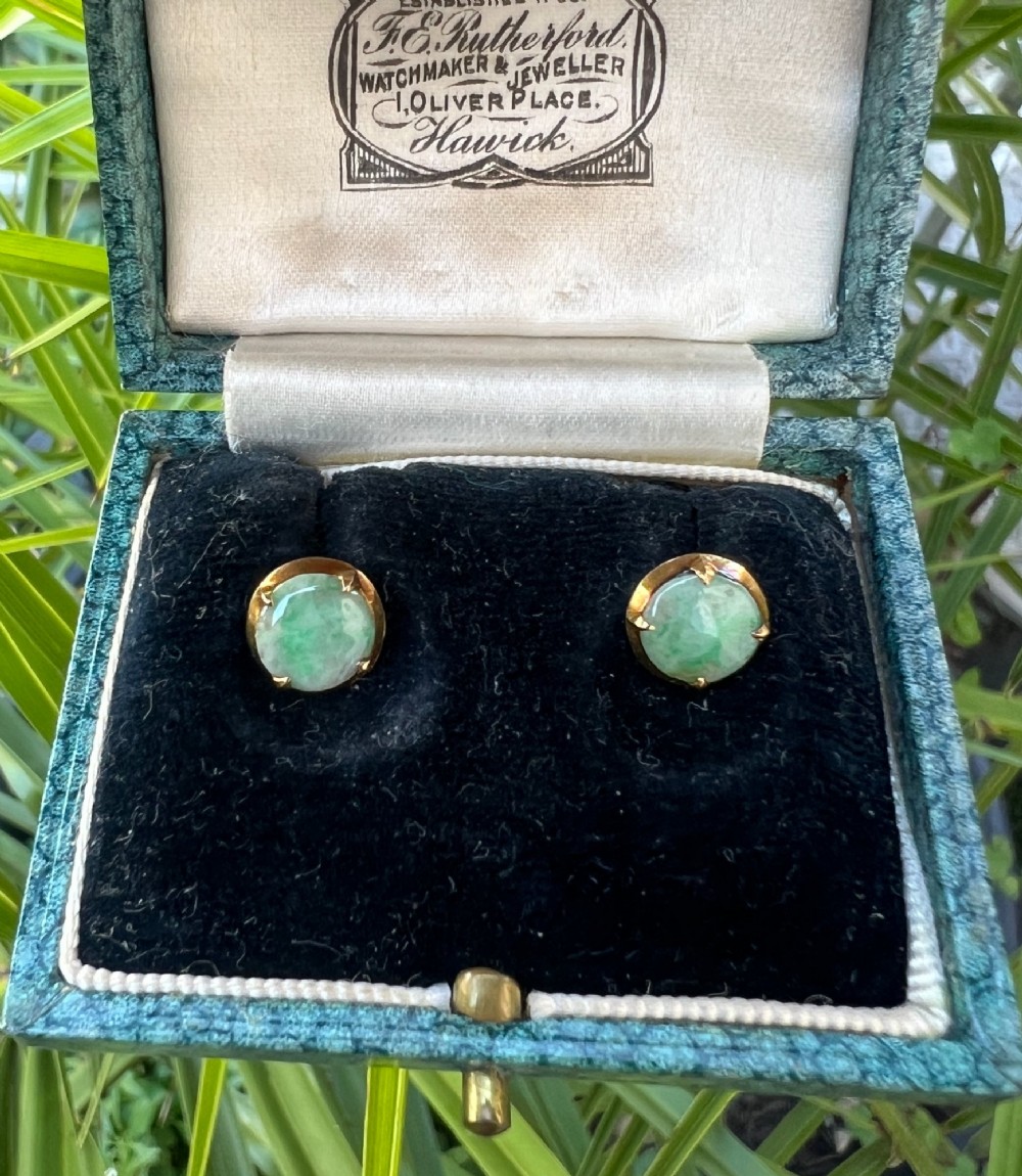 A pair of circular pale green jadeite cabochon stud earrings held in yellow gold claw settings. View V