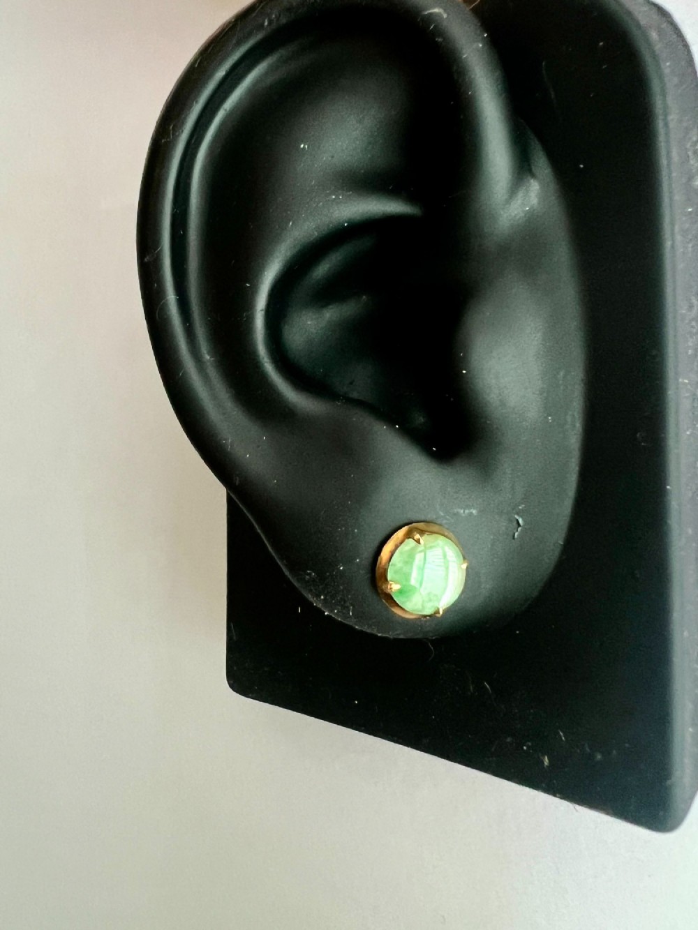 A pair of circular pale green jadeite cabochon stud earrings held in yellow gold claw settings. View VI