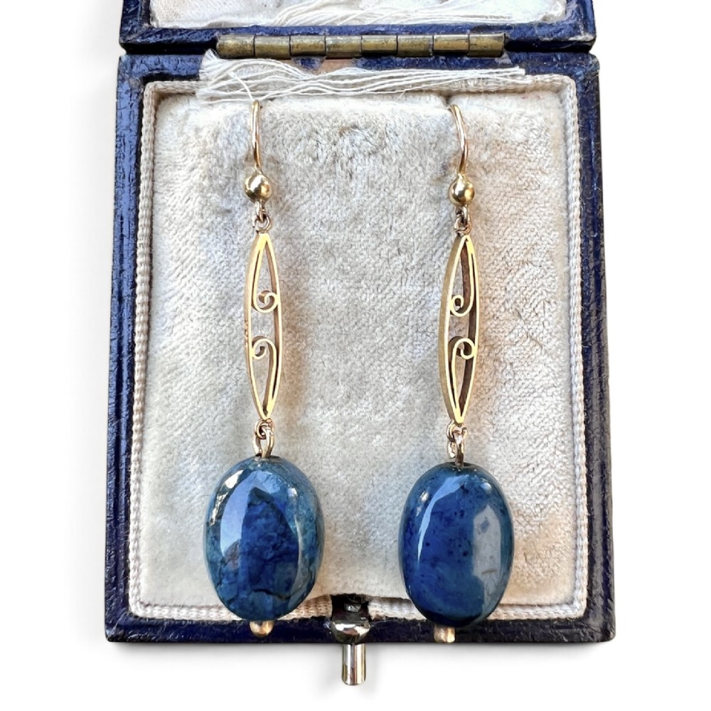 A pair of Edwardian yellow gold drop earrings featuring openwork scrollwork links suspended above oval blue apatite cabochon drops.
