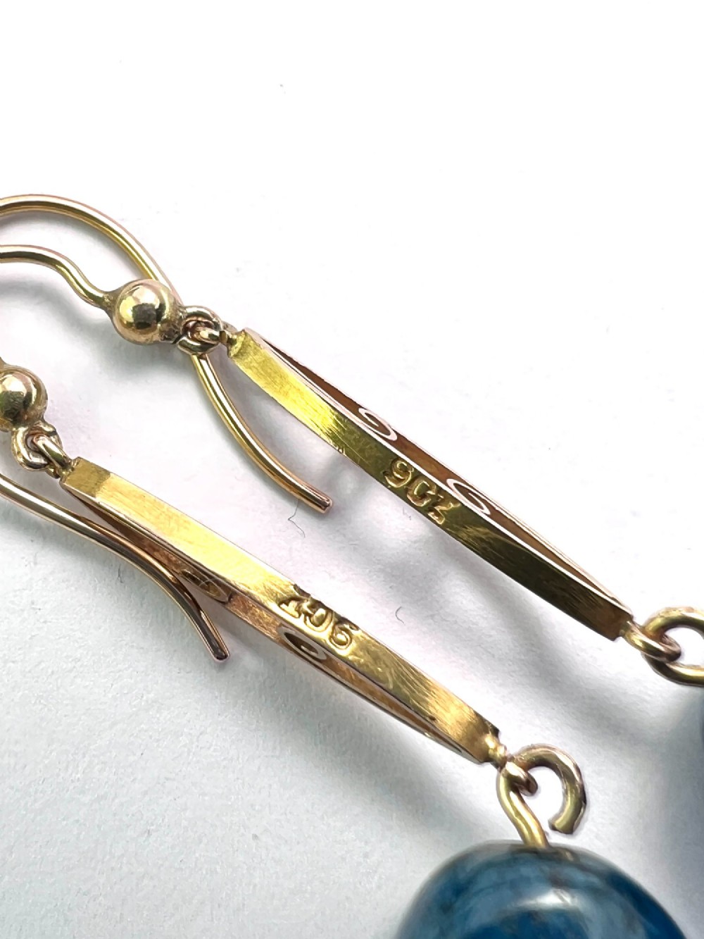 A pair of Edwardian yellow gold drop earrings featuring openwork scrollwork links suspended above oval blue apatite cabochon drops. View IV