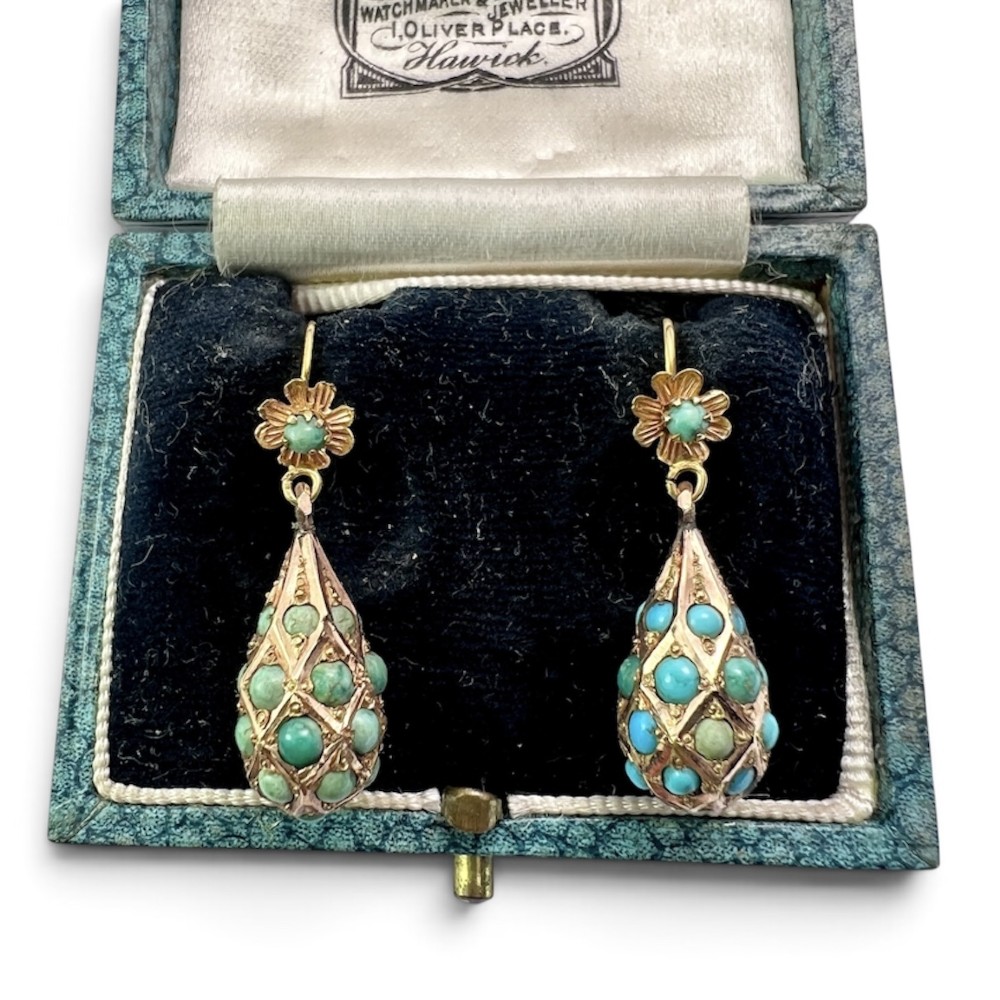 A pair of Victorian gold drop earrings featuring floral tops and lattice-engraved teardrop pendants set with turquoise cabochon stones.