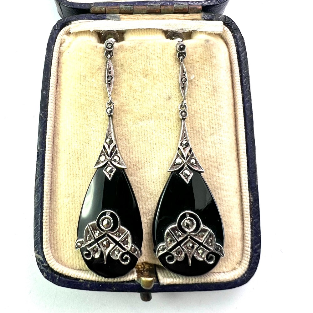 A pair of Art Deco drop earrings featuring polished teardrop-shaped black onyx stones suspended beneath decorative silver mounts set with marcasite stones. View II