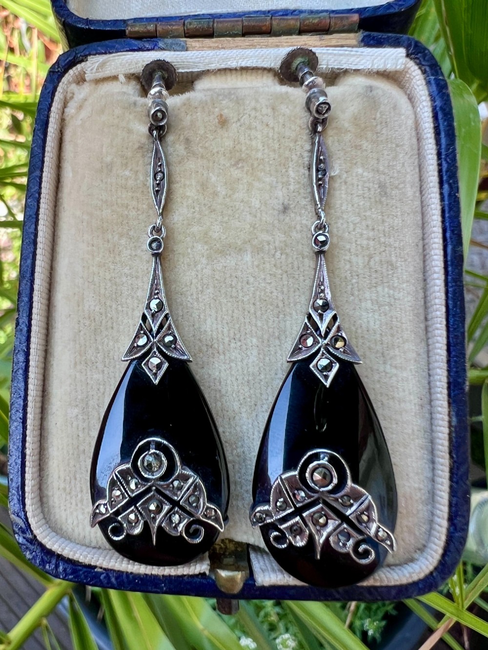A pair of Art Deco drop earrings featuring polished teardrop-shaped black onyx stones suspended beneath decorative silver mounts set with marcasite stones. View VII