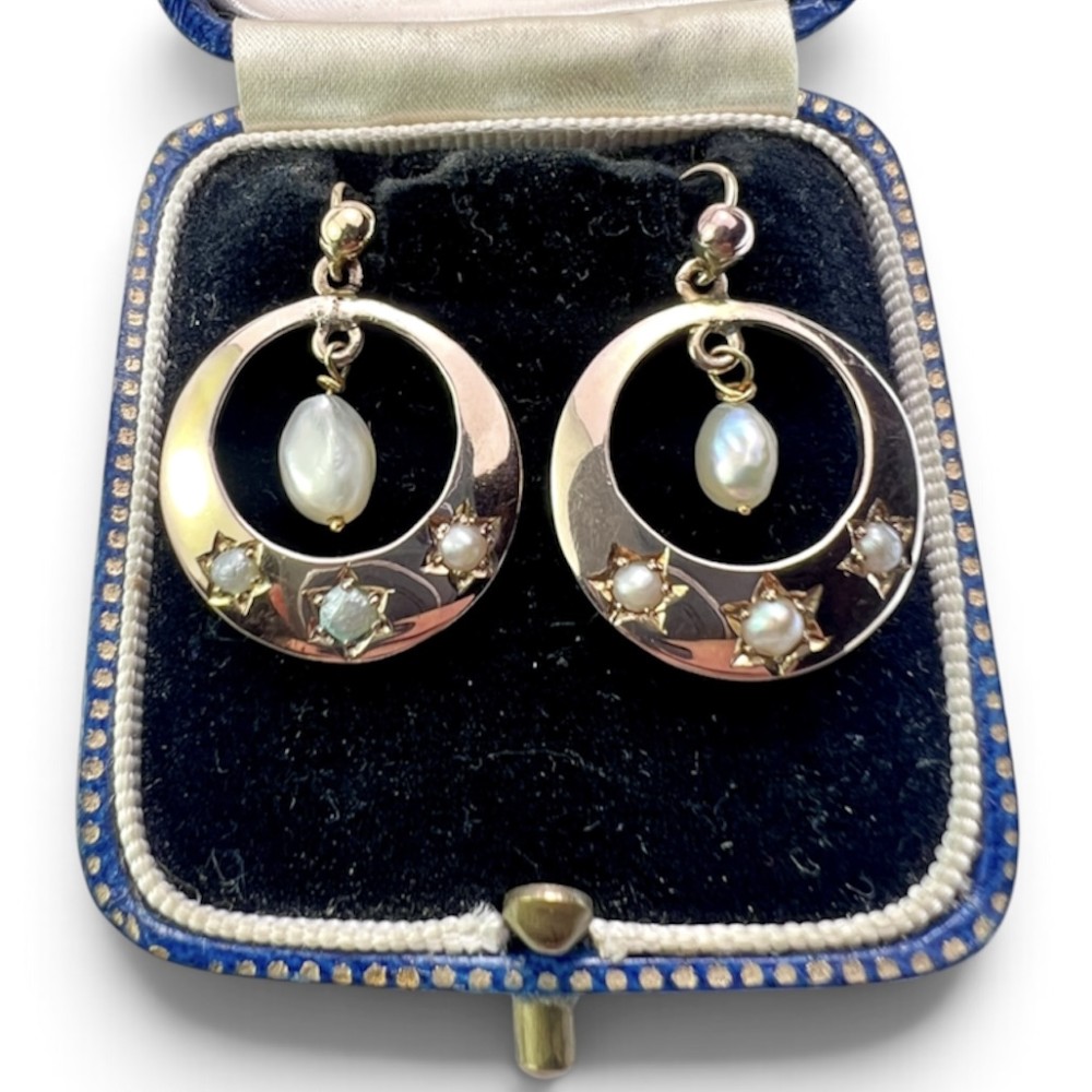 A pair of yellow gold Victorian crescent drop earrings featuring star-set seed pearls and a suspended central pearl drop.