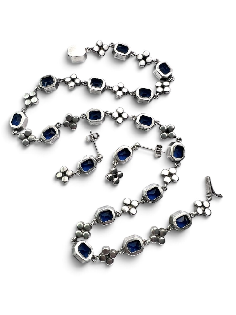 An Art Deco silver jewellery set comprising a link necklace and drop earrings with octagonal blue paste stones and clear cluster links. View IV
