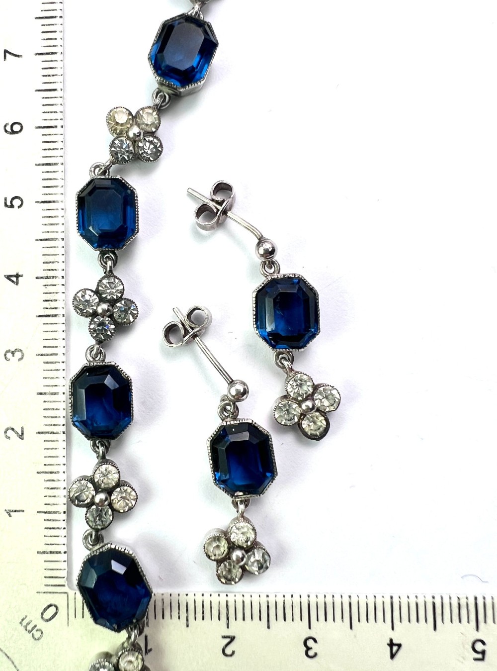 An Art Deco silver jewellery set comprising a link necklace and drop earrings with octagonal blue paste stones and clear cluster links. View VII