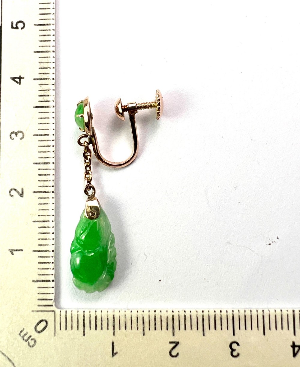 A pair of Art Deco 14ct gold drop earrings featuring circular green jade cabochons at the top connected by short chain links to teardrop-shaped carved green jade pendants. View V