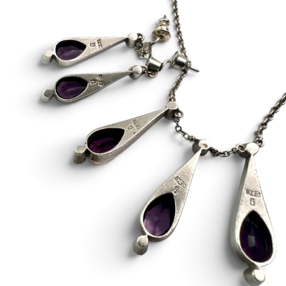 An Art Deco jewellery set featuring a silver chain necklace with teardrop purple paste drops and matching drop earrings. View III