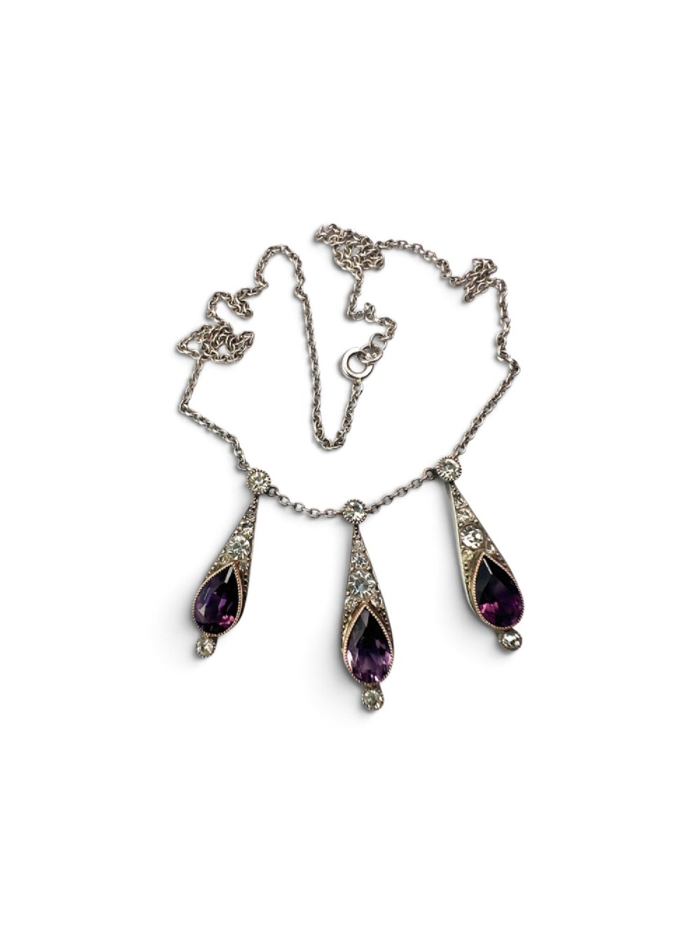 An Art Deco jewellery set featuring a silver chain necklace with teardrop purple paste drops and matching drop earrings. View IV