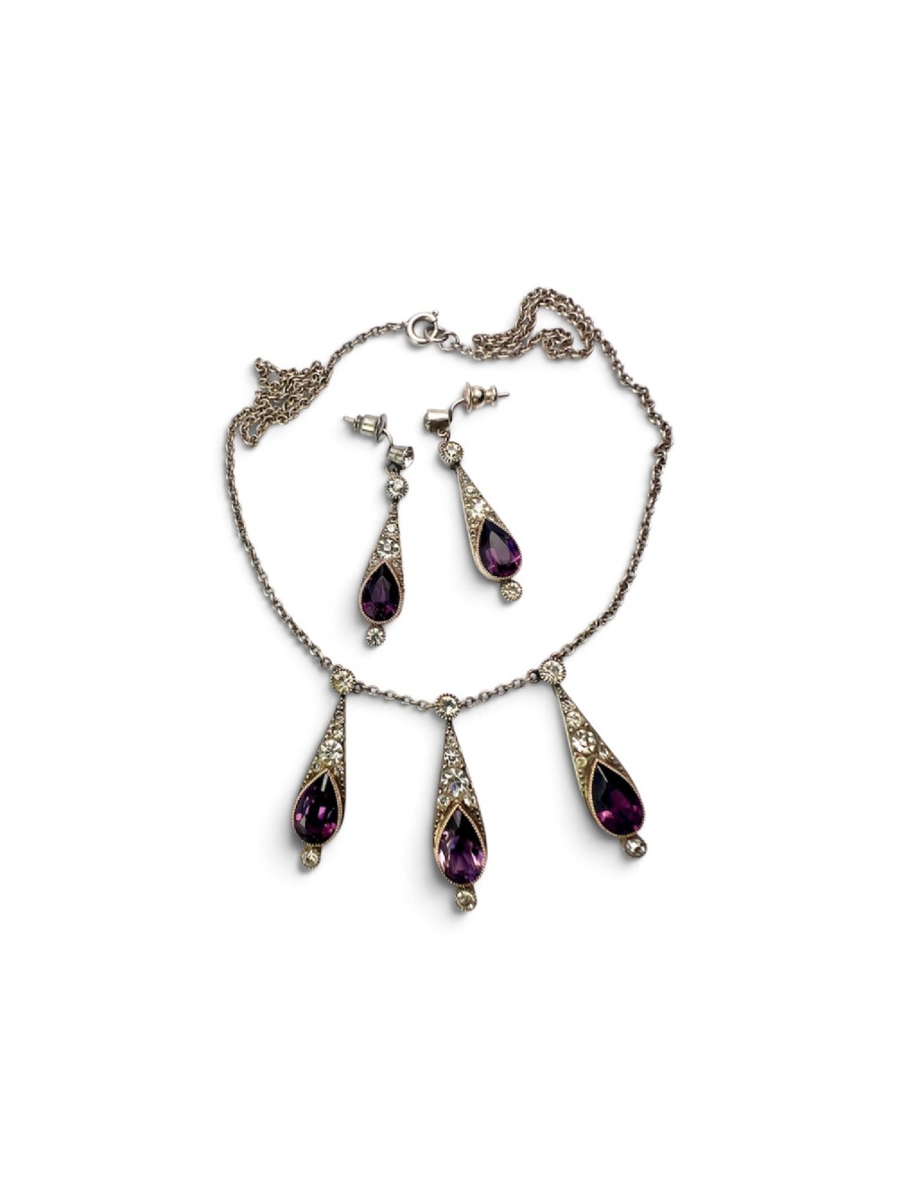 An Art Deco jewellery set featuring a silver chain necklace with teardrop purple paste drops and matching drop earrings. View VI