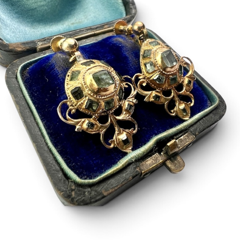 A pair of ornate Georgian yellow gold drop earrings featuring central step-cut green gemstones surrounded by smaller accent stones and scrollwork flourishes. View VI