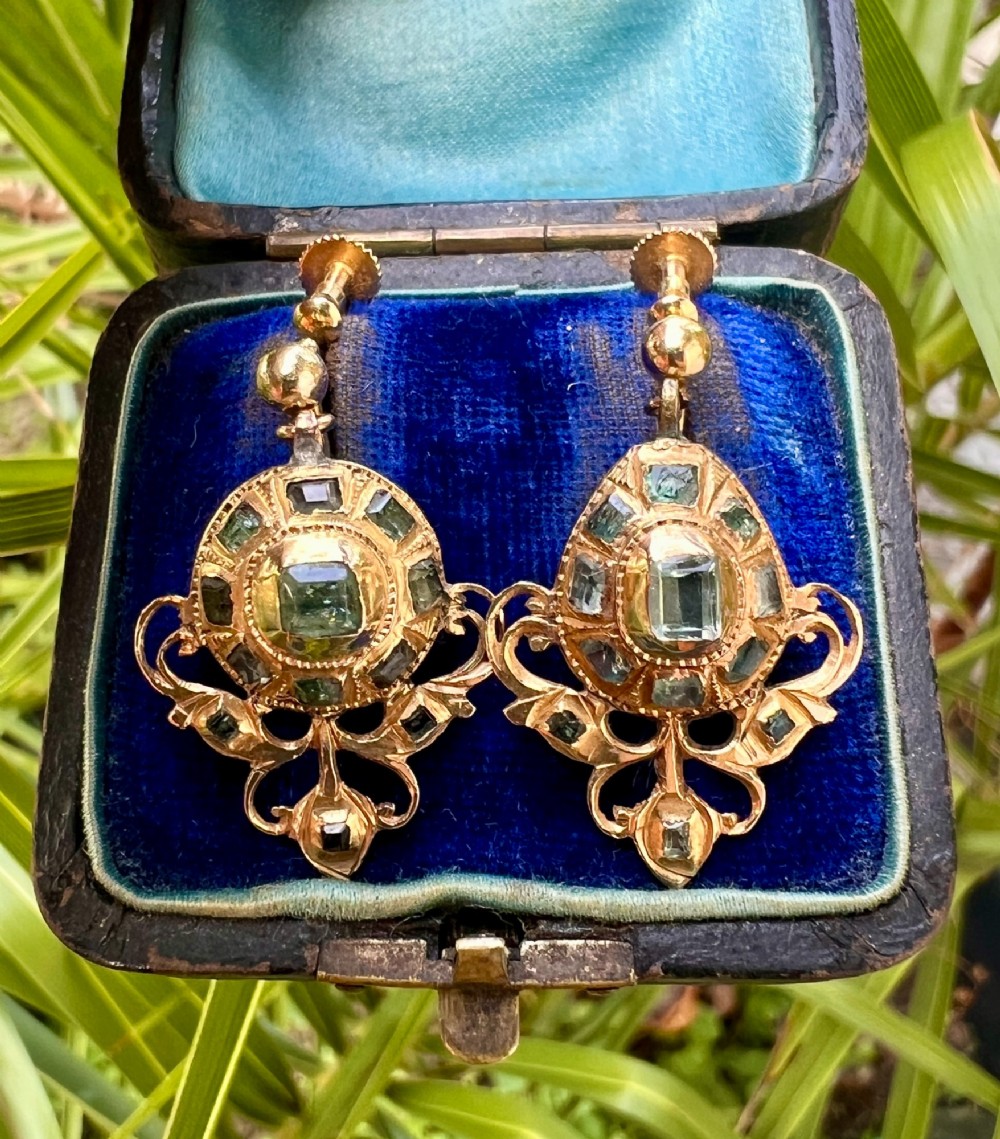 A pair of ornate Georgian yellow gold drop earrings featuring central step-cut green gemstones surrounded by smaller accent stones and scrollwork flourishes. View VII