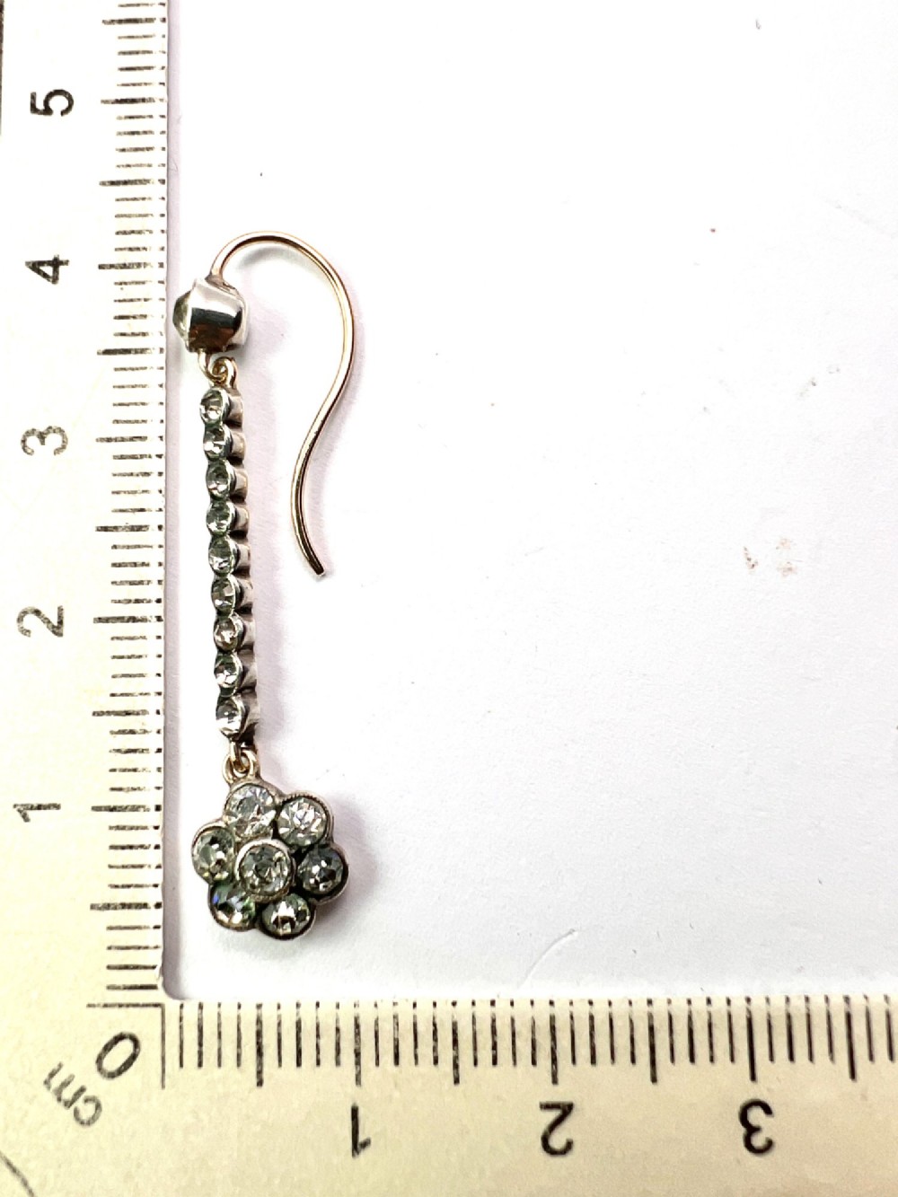 A pair of antique drop earrings featuring a linear row of round faceted paste stones terminating in a flower cluster drop. View VI
