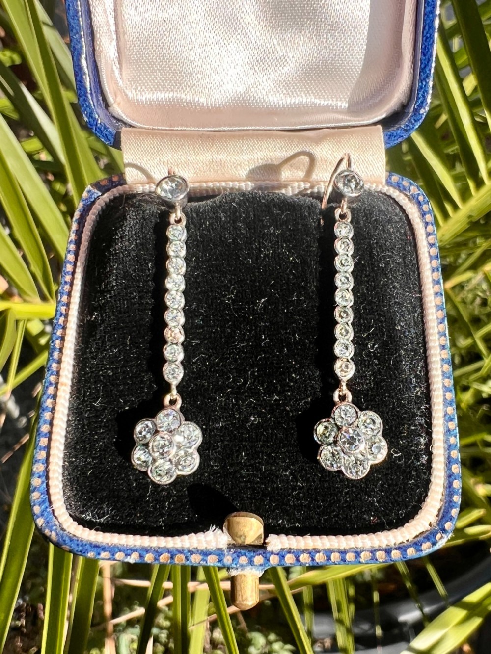 A pair of antique drop earrings featuring a linear row of round faceted paste stones terminating in a flower cluster drop. View VII