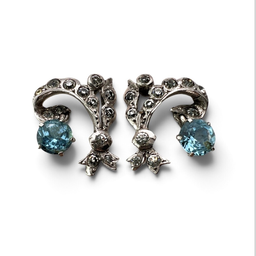 Pair of Edwardian silver screwback drop earrings featuring scrollwork set with clear paste stones and suspended light blue glass gems. View III