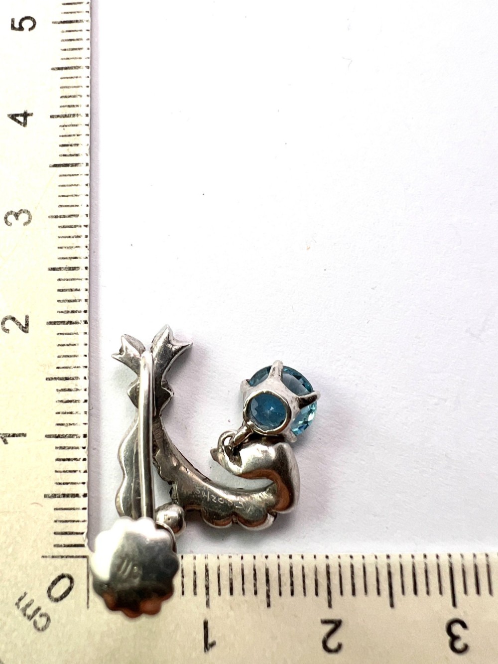 Pair of Edwardian silver screwback drop earrings featuring scrollwork set with clear paste stones and suspended light blue glass gems. View VII