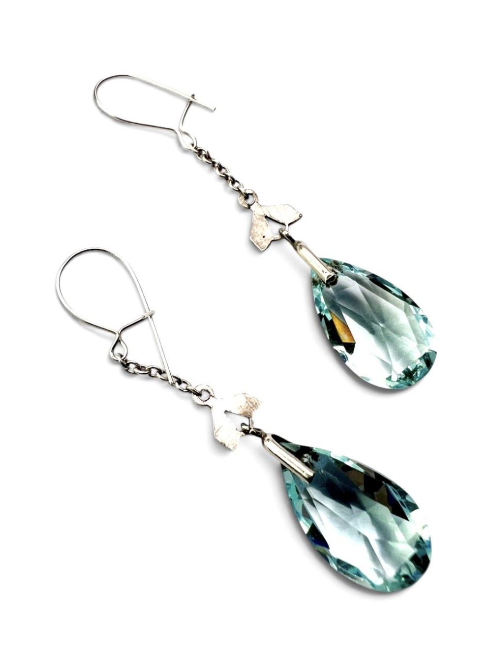 A pair of Edwardian silver drop earrings featuring faceted teardrop-shaped light blue paste stones hanging from delicate chains. View III