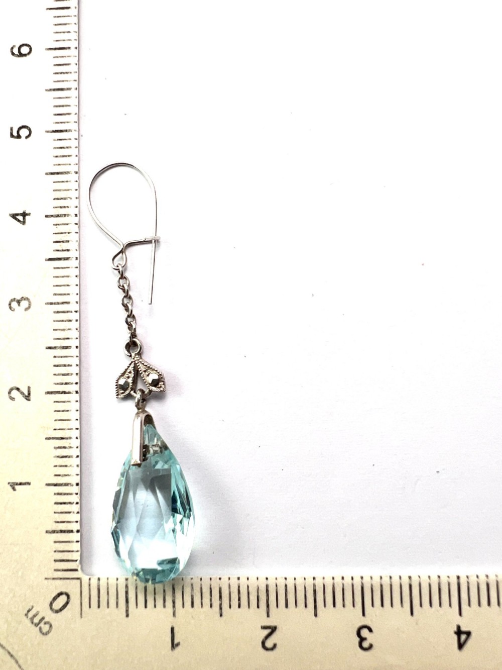 A pair of Edwardian silver drop earrings featuring faceted teardrop-shaped light blue paste stones hanging from delicate chains. View V