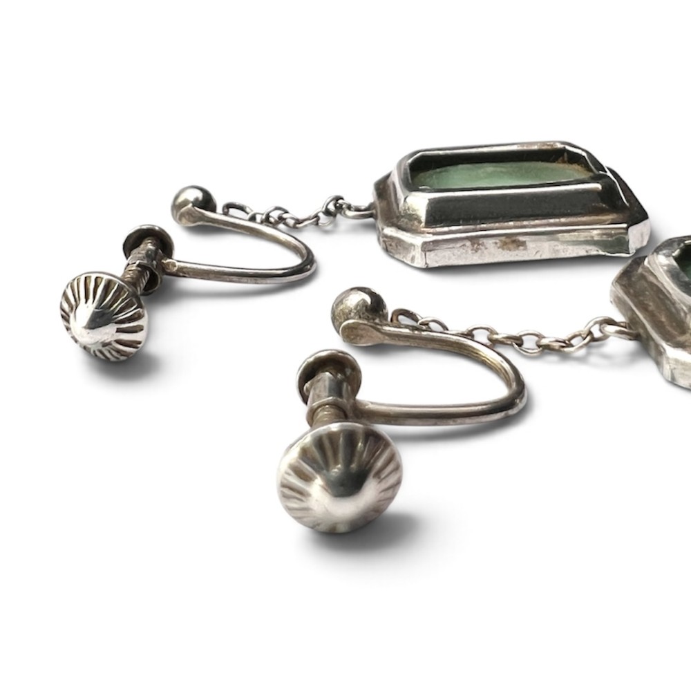 An Art Deco silver jewellery set featuring a rectangular ring and matching drop earrings inset with green glass plaques and clear step-cut paste stones. View IV