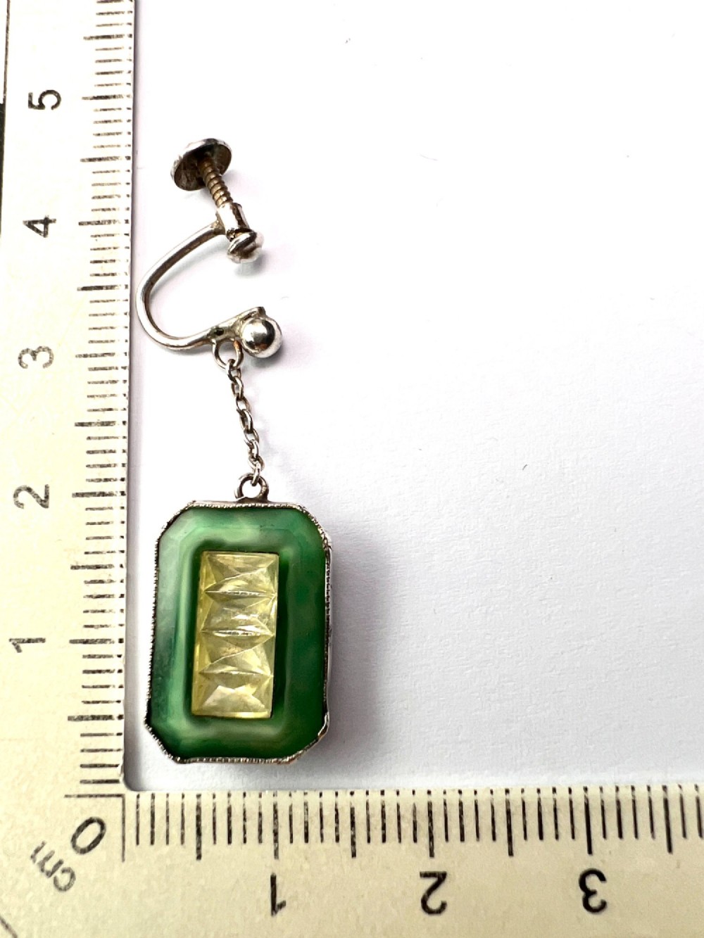 An Art Deco silver jewellery set featuring a rectangular ring and matching drop earrings inset with green glass plaques and clear step-cut paste stones. View X