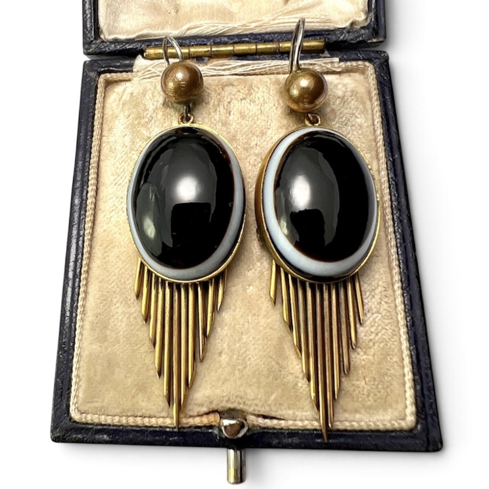 A pair of Victorian drop earrings featuring oval bullseye agate cabochons set in gold frames with graduating metallic fringe spikes below.