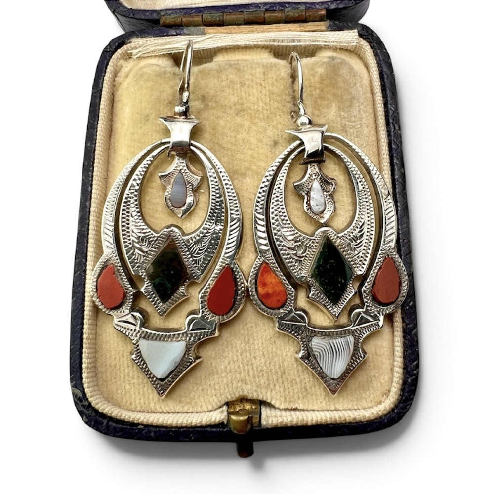A pair of Victorian sterling silver drop pendant earrings featuring hand-engraved openwork panels inlaid with geometric red jasper, green moss agate, and grey banded agate stones. View II
