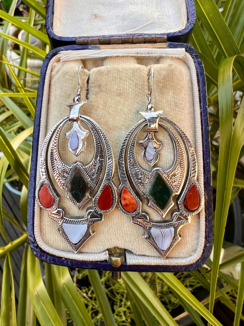 A pair of Victorian sterling silver drop pendant earrings featuring hand-engraved openwork panels inlaid with geometric red jasper, green moss agate, and grey banded agate stones. View VII
