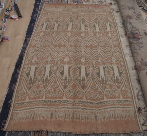 fig 1. A large handwoven antique ikat textile panel from Borneo displaying vertical rows of stylised human figures and chevron patterning in terracotta brown, cream, and grey.