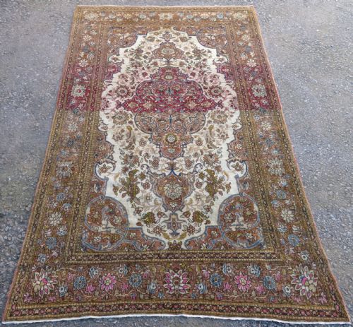 fig 1. An antique hand-knotted Isfahan wool rug featuring a red central floral medallion on an ivory field surrounded by terracotta and blue floral borders.
