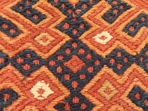 fig 1. An Ersari Turkmen flatweave wool torba featuring geometric motifs in terracotta red, navy, and ivory, complete with a long fringed lower border.