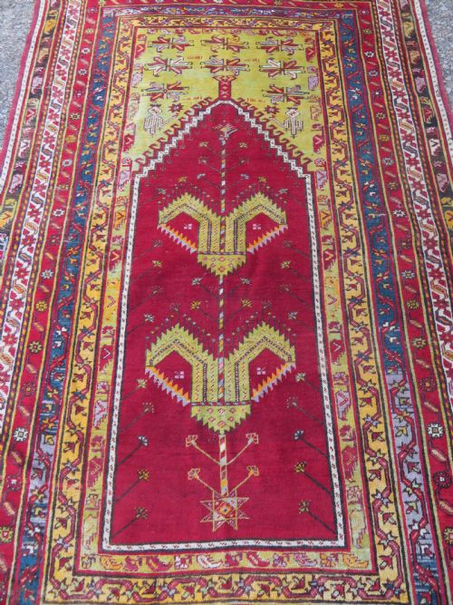 fig 1. An antique hand-knotted Turkish Kirsehir prayer rug featuring a central red mihrab arch framed by a yellow spandrel and multi-tiered geometric borders.