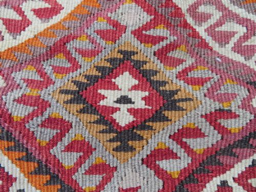 fig 1. A flatwoven Anatolian kilim grain sack featuring geometric diamond motifs in red, orange, cream, and brown wool with corner tassels.