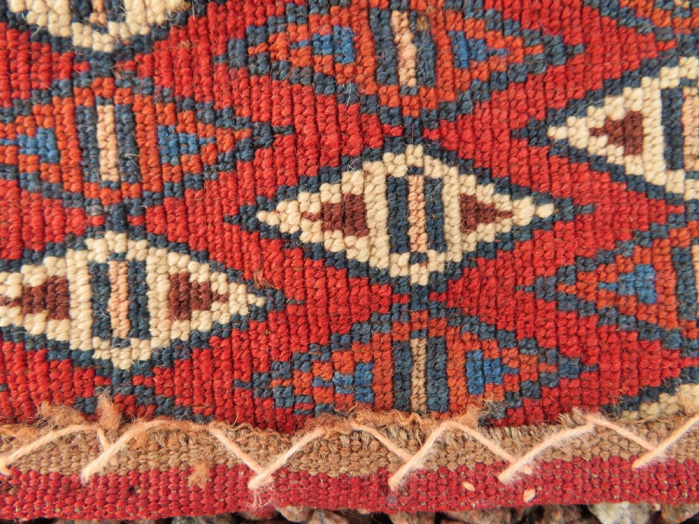 A rectangular hand-knotted Yomut Turkmen chuval rug featuring repeating gul motifs on a deep red field with a geometric border and diamond-patterned lower elem. View XXII