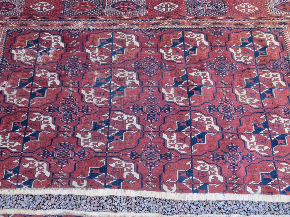An antique Tekke Turkmen main carpet and matching runner featuring traditional repeating gul motifs in deep red, navy blue, and ivory hand-woven wool. View IV