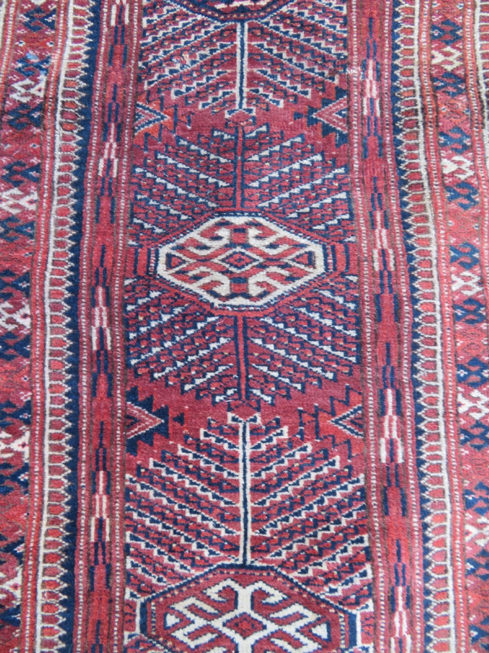 An antique Tekke Turkmen main carpet and matching runner featuring traditional repeating gul motifs in deep red, navy blue, and ivory hand-woven wool. View V