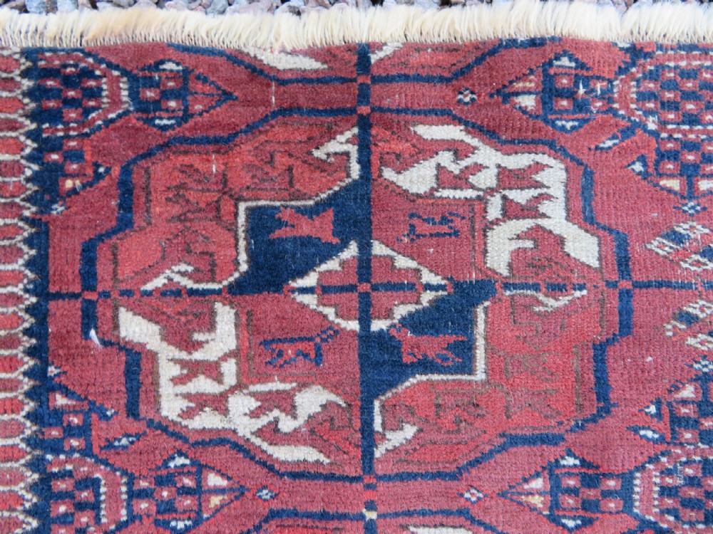 An antique Tekke Turkmen main carpet and matching runner featuring traditional repeating gul motifs in deep red, navy blue, and ivory hand-woven wool. View VII