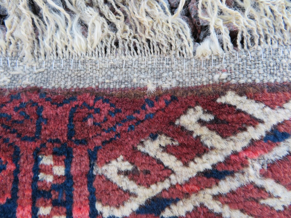 An antique Tekke Turkmen main carpet and matching runner featuring traditional repeating gul motifs in deep red, navy blue, and ivory hand-woven wool. View XII