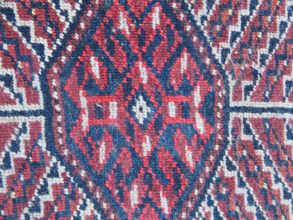 An antique Tekke Turkmen main carpet and matching runner featuring traditional repeating gul motifs in deep red, navy blue, and ivory hand-woven wool. View XVII