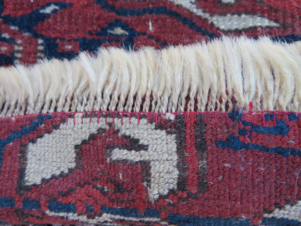 An antique Tekke Turkmen main carpet and matching runner featuring traditional repeating gul motifs in deep red, navy blue, and ivory hand-woven wool. View XX