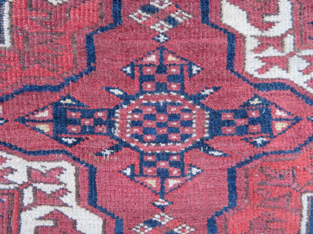An antique Tekke Turkmen main carpet and matching runner featuring traditional repeating gul motifs in deep red, navy blue, and ivory hand-woven wool. View XXI