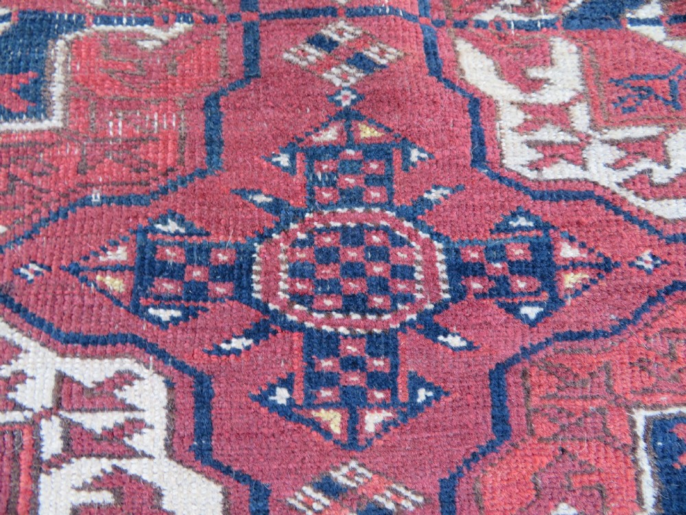 An antique Tekke Turkmen main carpet and matching runner featuring traditional repeating gul motifs in deep red, navy blue, and ivory hand-woven wool. View XXII