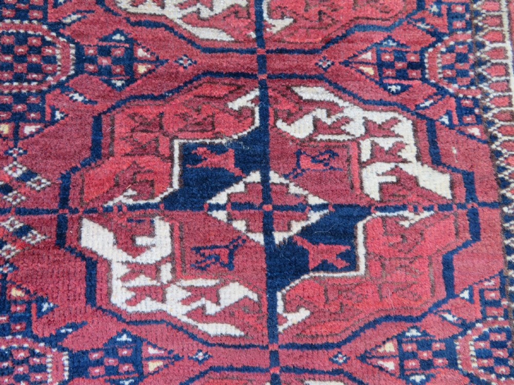 An antique Tekke Turkmen main carpet and matching runner featuring traditional repeating gul motifs in deep red, navy blue, and ivory hand-woven wool. View XXIII