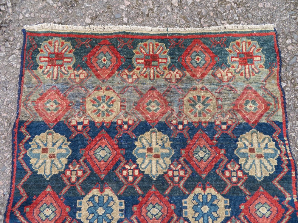 A long, narrow hand-knotted wool runner featuring a repeating geometric Mina Khana floral lattice pattern in navy blue, terracotta red, and cream tones. View VIII