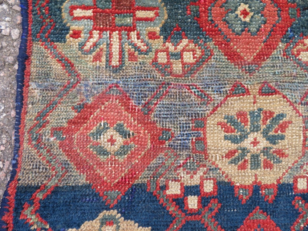 A long, narrow hand-knotted wool runner featuring a repeating geometric Mina Khana floral lattice pattern in navy blue, terracotta red, and cream tones. View XI