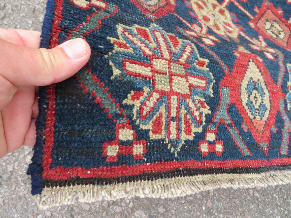 A long, narrow hand-knotted wool runner featuring a repeating geometric Mina Khana floral lattice pattern in navy blue, terracotta red, and cream tones. View XII