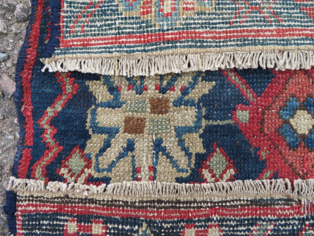 A long, narrow hand-knotted wool runner featuring a repeating geometric Mina Khana floral lattice pattern in navy blue, terracotta red, and cream tones. View XX